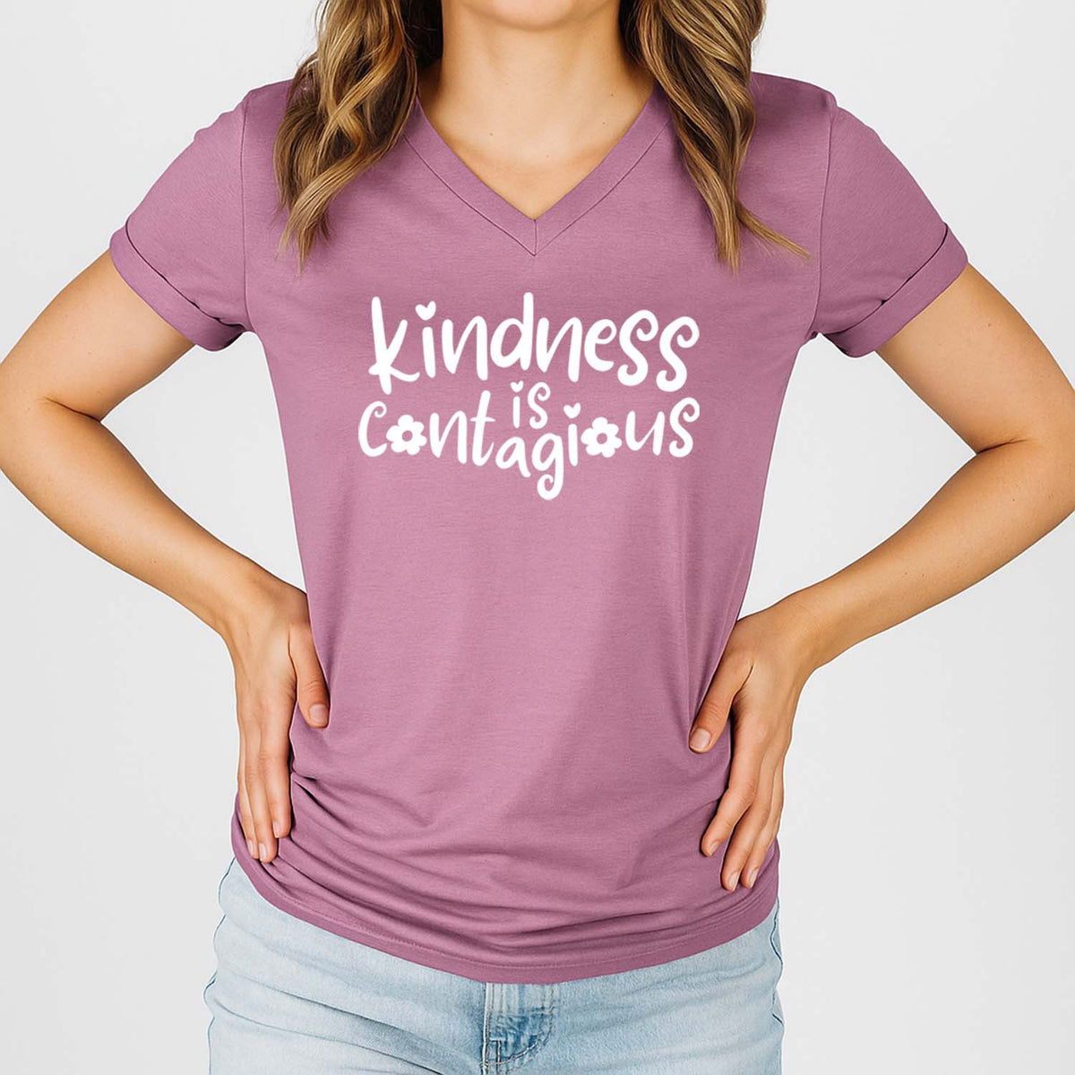Person wearing a purple t-shirt with 'kindness is contagious' text on a plain background