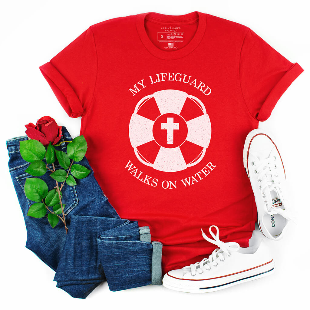A vibrant red t-shirt with the phrase 'My Lifeguard Walks On Water' in bold white letters, referencing Jesus's miracle from the Bible