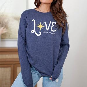 Model wearing navy Christmas shirt that reads love came down