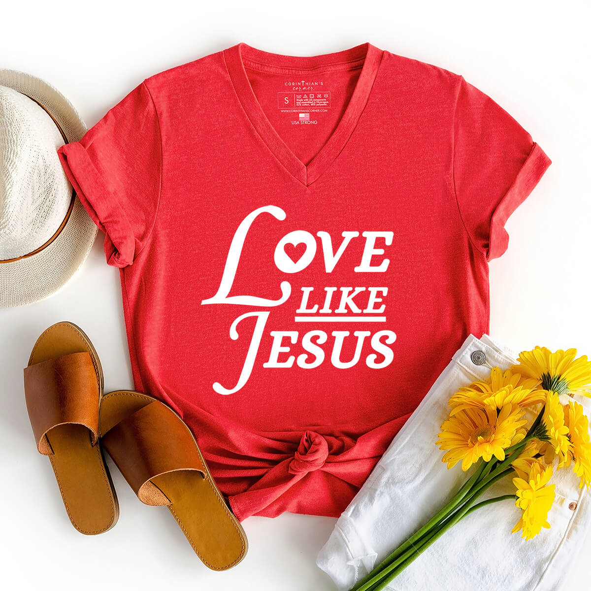 Love like Jesus graphic v-neck shirt styled with flowers, sandals, and a summer hat 
