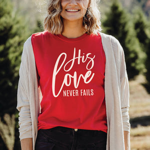 Woman in the woods wearing a vibrant His love never fails t-shirt