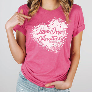 Model pointing at her pink love one another John 13:34 t-shirt