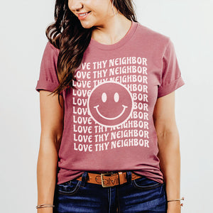 Smiling model wearing a love thy neighbor Christian top in mauve