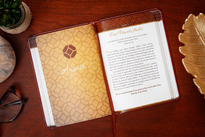Open devotional with textured cover and visible text on a wooden surface