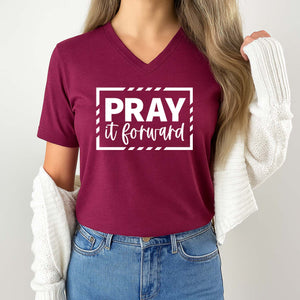 Person wearing a maroon t-shirt with 'PRAY it forward' text on a plain background