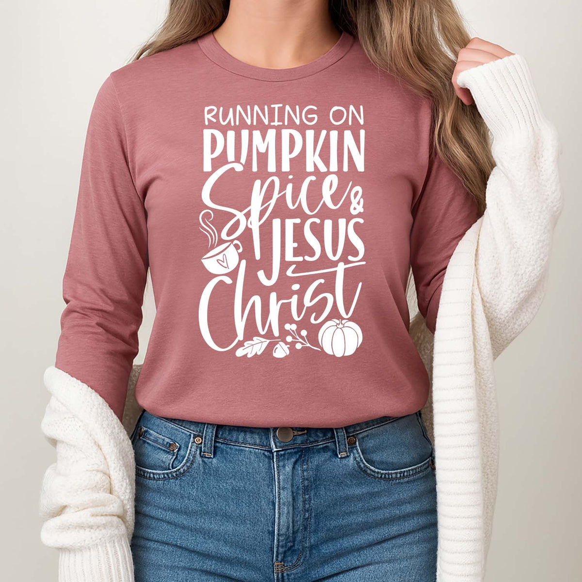Person wearing a pink long-sleeve shirt with text 'Running on Pumpkin Spice & Jesus Christ' against a neutral background.
