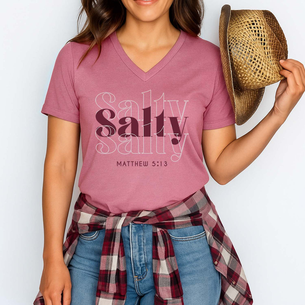 Person wearing a pink t-shirt with 'Salty Salty Matthew 5:13' text, holding a straw hat