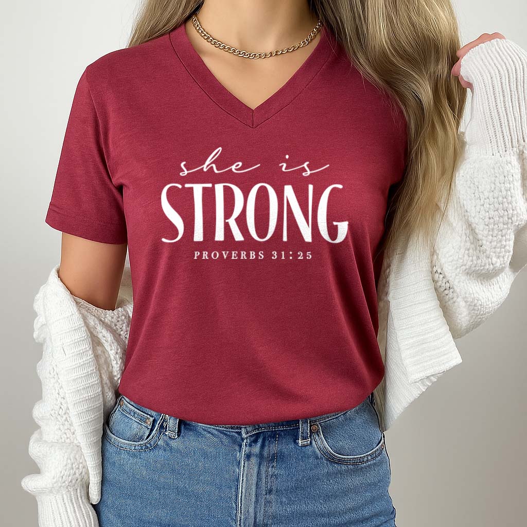 Red t-shirt with 'She is Strong' text worn by a person against a neutral background
