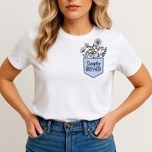 Woman wearing a white t-shirt with a floral design and 'Simply Blessed' text on a plain background