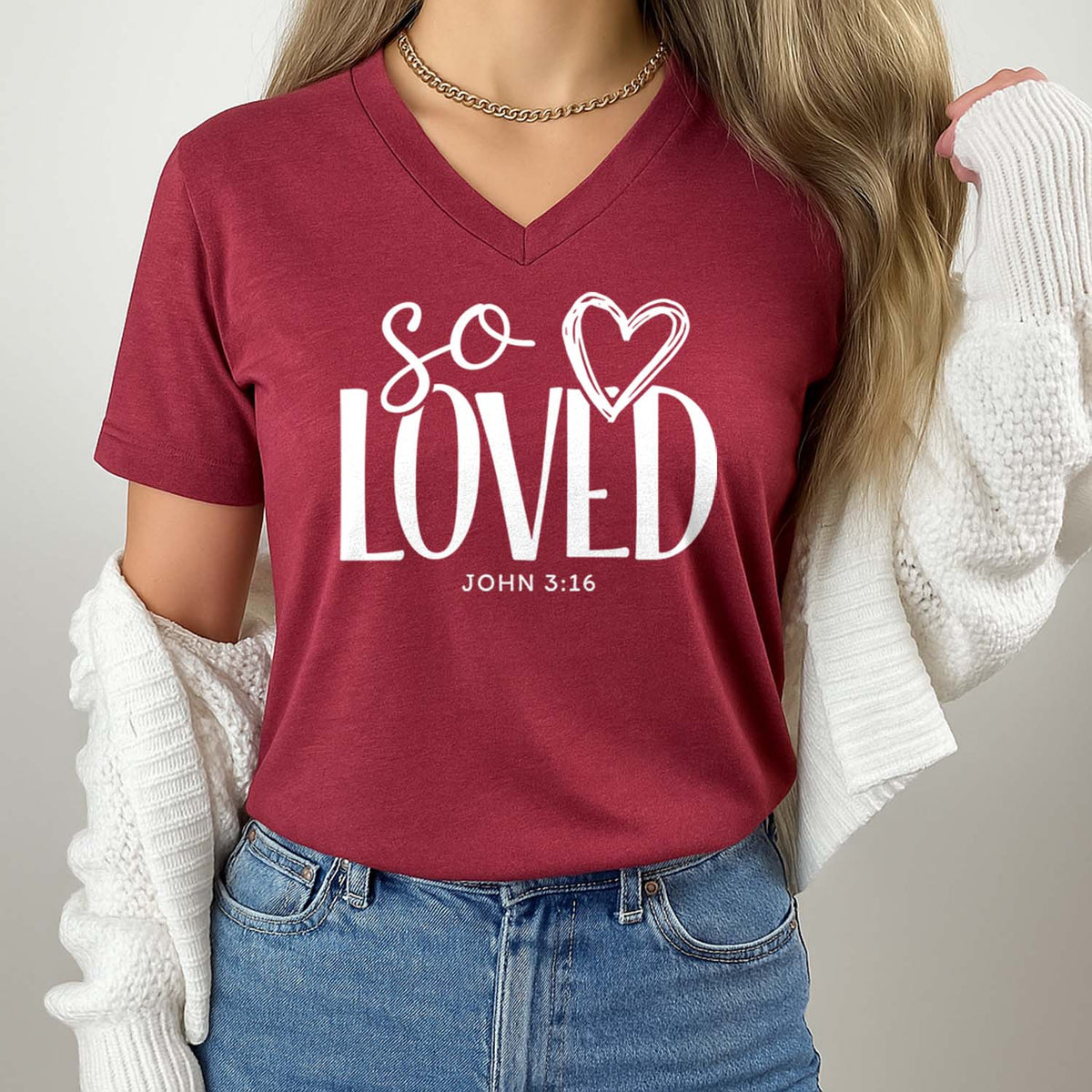Red t-shirt with 'So Loved' text worn by a person, against a neutral background