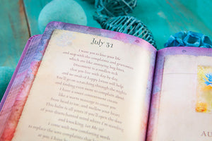Open devotional with text and colorful watercolor design on a teal background