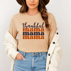 Woman wearing a beige Christian long sleeve with 'thankful mama' while standing against a plain background