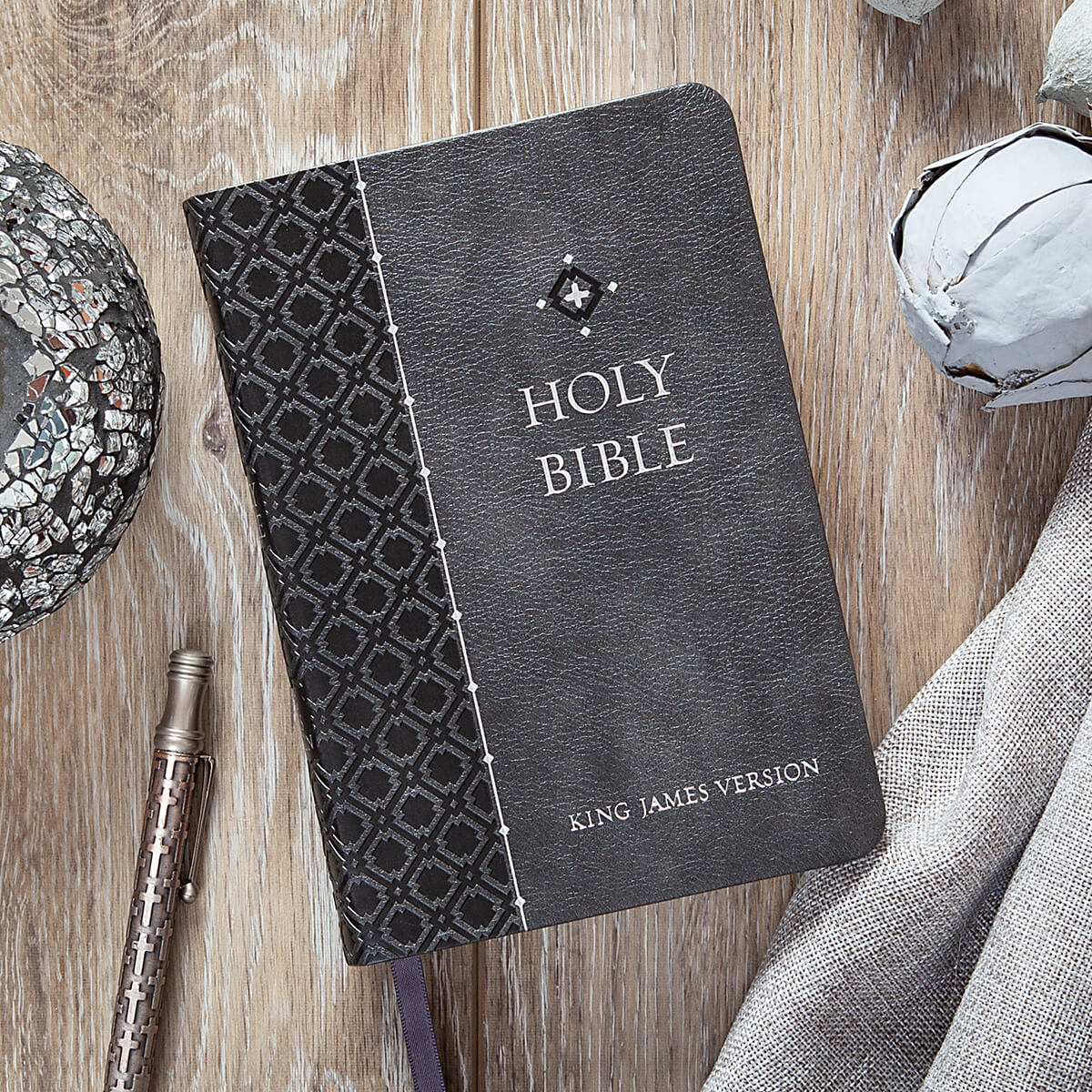 Black leather-bound Bible with decorative cover on a wooden surface