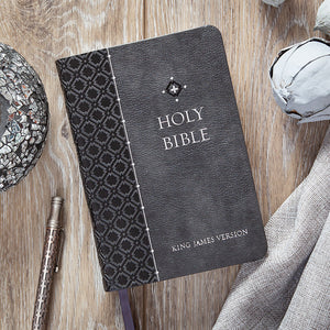Black leather-bound Bible with decorative cover on a wooden surface