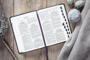 Open Bible with text on a wooden surface with decorative items