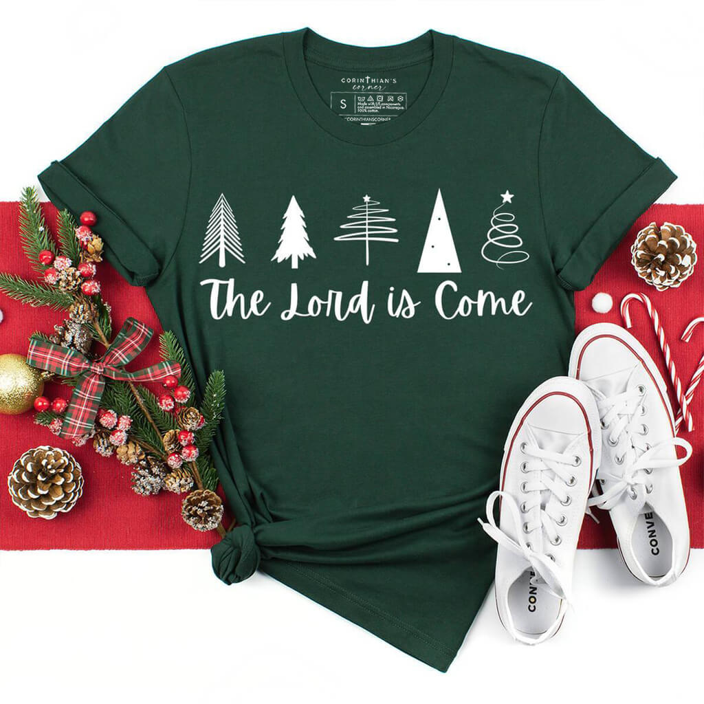 Christmas tree design with "the Lord is come" written in script font on a dark green shirt