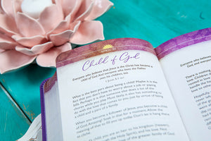 Open book with a colorful bookmark titled 'Child of God' on a teal surface with a pink flower.