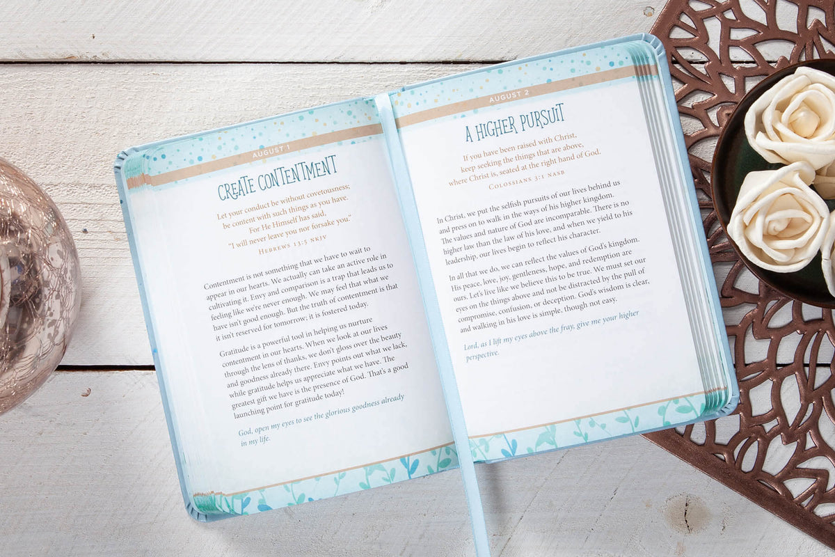 Open daily devotional with text on a wooden surface with decorative elements