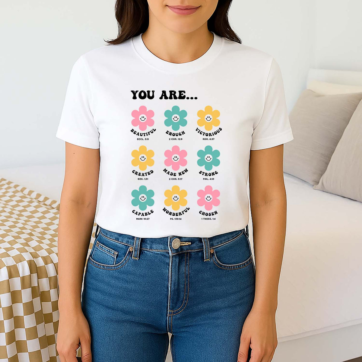 Woman wearing a white t-shirt with colorful flower graphics and Biblical text.