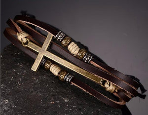 Leather cross bracelet laying against a dark stone