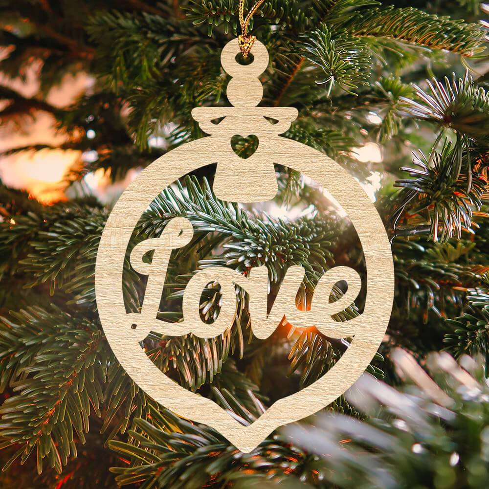Closeup of a "love" Christmas ornament hanging from a tree