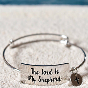 Stainless steel faith-inspired bracelet laying on the beach